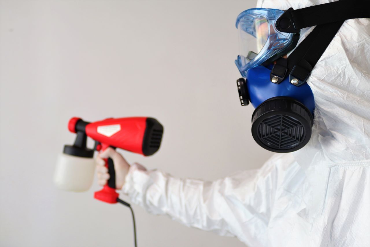 creative-02 A worker in protective gear uses a disinfectant spray indoors.